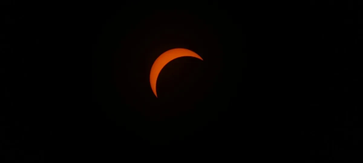 Photo of thin crescent of Sun visible against a dark black sky